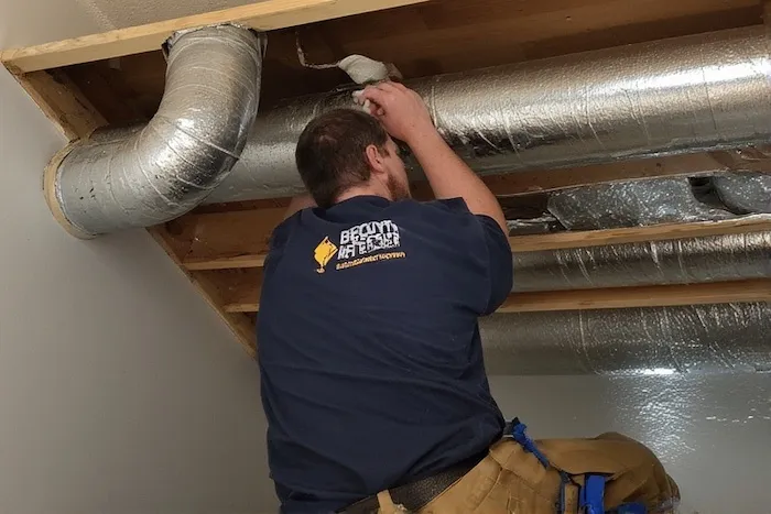 Certified HVAC technician professionally installing ductwork for a heat recovery ventilator system